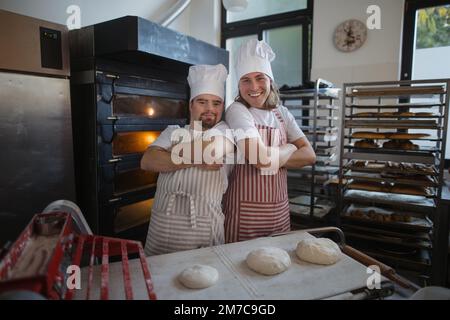 Ritratto dell'uomo con sindrome di Down e il suo collega in panetteria. Concetto di integrazione delle persone con disabilità nella società. Foto Stock