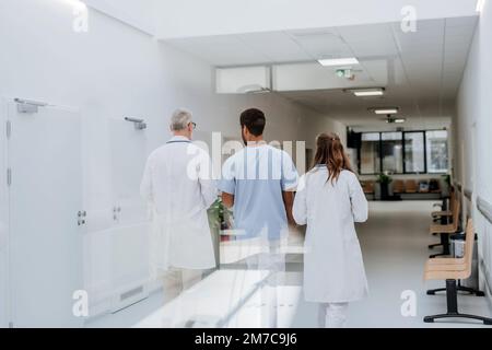 Vista posteriore del personale medico nel corridoio dell'ospedale. Foto Stock