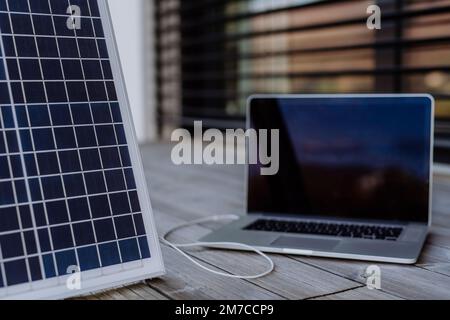 Primo piano della ricarica del notebook tramite pannello solare. Foto Stock