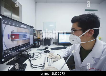 HANGZHOU, CINA - 9 GENNAIO 2023 - Un radiologo presso un centro di servizi sanitari della comunità esamina e scatta foto dei polmoni di un cittadino con un CT richiede Foto Stock