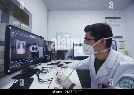 HANGZHOU, CINA - 9 GENNAIO 2023 - Un radiologo presso un centro di servizi sanitari della comunità esamina e scatta foto dei polmoni di un cittadino con un CT richiede Foto Stock