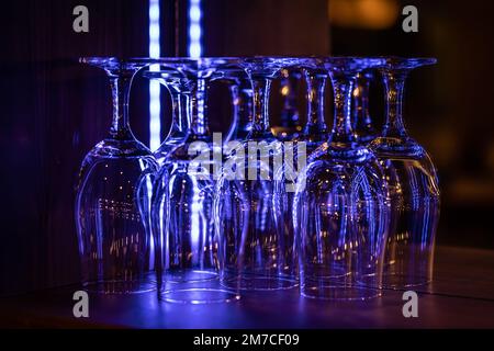 Bicchieri da vino puliti nel bar notturno che si illuminano con colori al neon. Foto Stock
