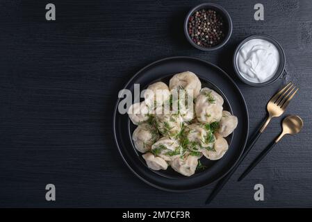 Tradizionale pelmeni russo, ravioli, gnocchi con carne su sfondo nero. Foto Stock