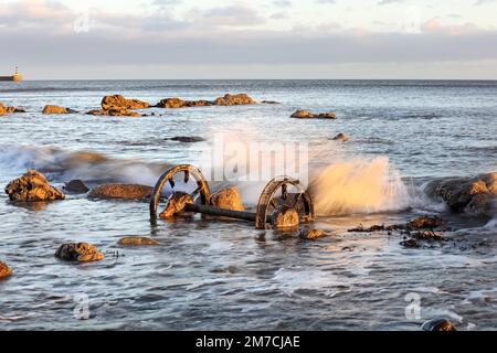 Old chaldron Wagon Wheels sulla spiaggia chimica con il faro di Seaham Harbour Beyond, Durham Heritage Coast, Seaham, County Durham, Regno Unito Foto Stock