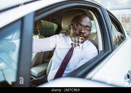 Ritratto di un bell'uomo d'affari afroamericano di successo alla guida della sua auto Foto Stock