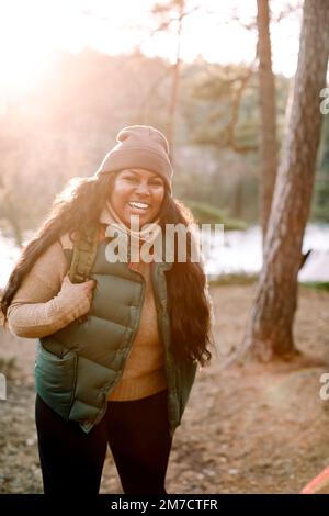 Ritratto di felice giovane donna in piedi nella foresta Foto Stock