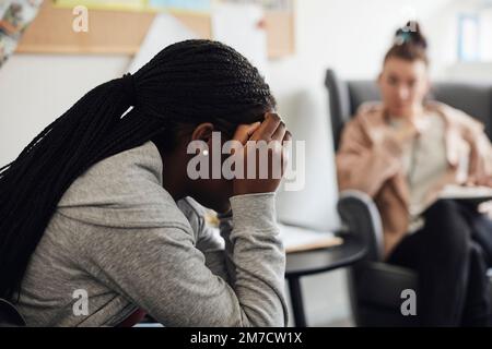 Studente depresso di sesso femminile che discute con il consulente in ufficio scolastico Foto Stock