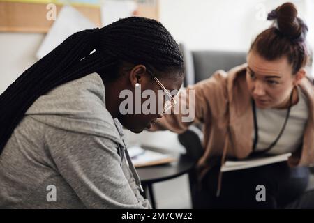 Salute mentale professionale consolante triste studente femminile in ufficio scolastico Foto Stock