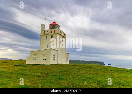 Faro e paesaggio a Dyrholaey, Islanda Dyrhólaey ('isola di collina del door'), precedentemente conosciuto dai marinai come capo Portland, è un piccolo luogo del promontorio Foto Stock