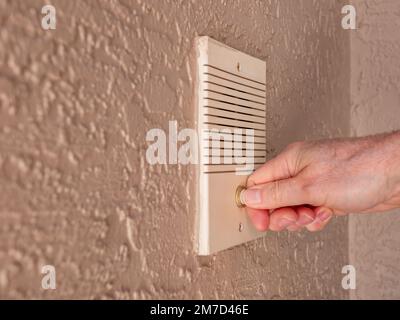 Campanello che suona con il pollice. Primo piano di mano maschile spingendo a casa citofono porta pulsante campana. Foto Stock