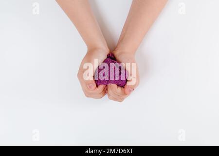 Sabbia cinetica viola. Il bambino scolpisce e gioca con la sabbia. Vista dall'alto. Sfondo bianco. Spazio per il testo Foto Stock