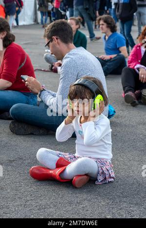 Bambina ad un concerto rock con cuffie per proteggere i suoi timpani Foto Stock