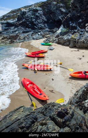 Kayak da mare al largo della costa di Angelsey, Galles settentrionale, con un'emopta kayak su una spiaggia deserta. Foto Stock