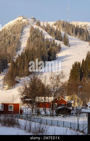 Beautiful little wooden mountain houses, huts with a ski slope surrounded by forest on a sunny winter day. Skiing resort in Sweden, Funasdalen covered Foto Stock