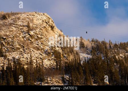 Beautiful ski slope in Funasdalen, Sweden with ski lift, gondola going up the hill surrounded by forest on a sunny winter day. Skiing resort in Sweden Foto Stock