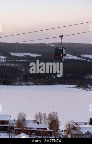Beautiful ski slope in Funasdalen, Sweden with ski lift, gondola going up the hill surrounded by forest on a sunny winter day. Skiing resort in Sweden Foto Stock