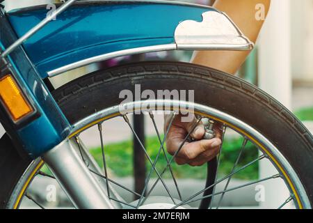 Mani di un uomo controllare la pressione del generatore di gas e gonfiare uno pneumatico su una motocicletta con un compressore pneumatico. Man controllo della pressione dell'aria e riempimento della pressione dei pneumatici Foto Stock