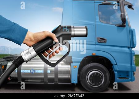Mano con ugello di rifornimento H2 sullo sfondo di un semi-camion a celle a combustibile idrogeno con serbatoio del gas a bordo. Concetto di veicolo commerciale ecocompatibile Foto Stock