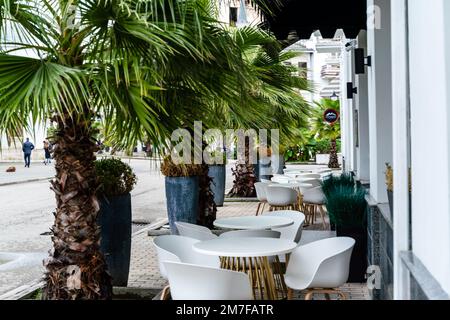 Street cafè con sedie bianche, verde fogliame intorno. Senza persone, turismo, viaggi. Foto Stock