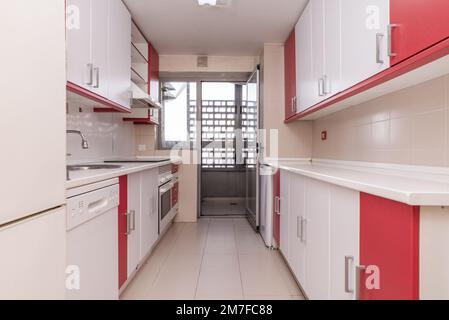 cucina di una casa al piano terra con accesso ad una terrazza con mobili bicolore, ripiani bianchi e elettrodomestici bianchi integrati Foto Stock