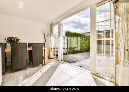 un soggiorno con porte scorrevoli in vetro che conducono al patio e all'area giardino di fronte all'edificio degli appartamenti Foto Stock