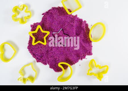 Sabbia cinetica viola, stampi in plastica per sabbia. Vista dall'alto. Sfondo bianco, vista ravvicinata Foto Stock