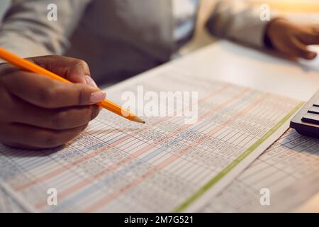 Contabile finanziario seduto in ufficio, facendo documenti e lavorando con fogli di calcolo Foto Stock