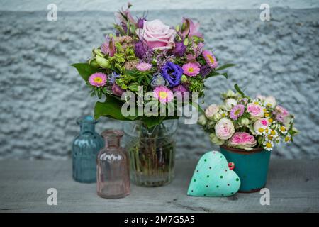 Piccolo bouquet di fiori con rose rosa e un cuore Foto Stock