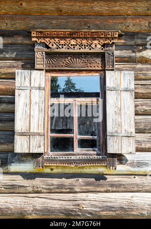 Finestre di vecchia casa di tronchi tradizionale russa con rivestimento in legno intagliato Foto Stock