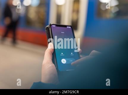Primo piano della chiamata telefonica con le dita di una donna davanti al treno sulla stazione ferroviaria Foto Stock