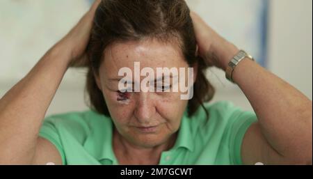 Donna anziana con capelli lividi che regolano il viso Foto Stock