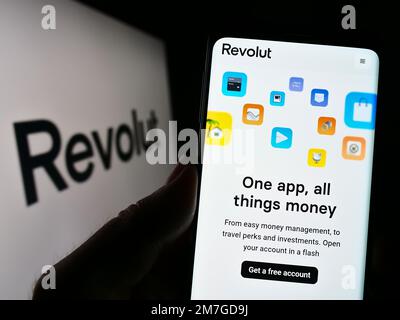 Persona che tiene il cellulare con il sito web della società britannica fintech Revolut Ltd. Sullo schermo di fronte al logo. Messa a fuoco al centro del display del telefono. Foto Stock