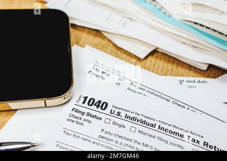 Primo piano del modulo fiscale individuale statunitense e dello smartphone sul tavolo. Stagione fiscale Foto Stock