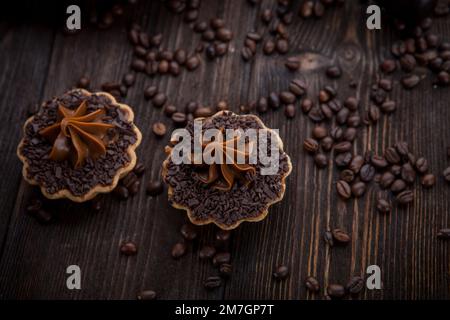 Caffè aromatico appena preparato su uno sfondo di chicchi di caffè e biscotti cremosi. Atmosfera da caffè Foto Stock