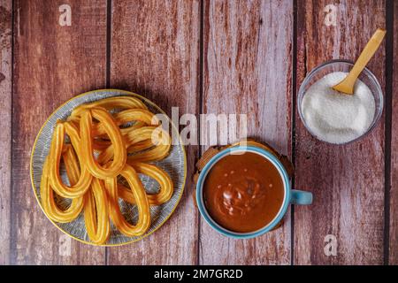 Cioccolata calda con churros in una tazza bianca e blu, tipica colazione spagnola su un tavolo di legno Foto Stock