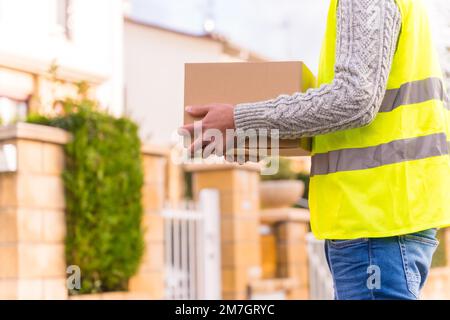 Vettore di consegna del pacco con una scatola da un negozio online, consegna a casa Foto Stock