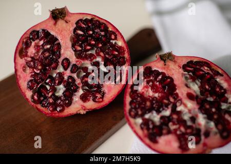 Primo piano di semi di melograno su tagliere di legno in cucina Foto Stock