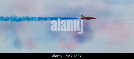 Un aereo Red Arrows BAE Systems Hawk T1 che esce fumo blu in un approccio ad una manovra di crossover in uno schermo su Eastbourne, East Sussex Foto Stock