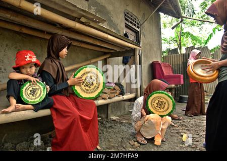 Un gruppo di bambini rurali che giocano a Rebana, mentre si stanno allenando per una performance musicale islamica a Buni, Bekasi , Giava Occidentale, Indonesia. Foto Stock