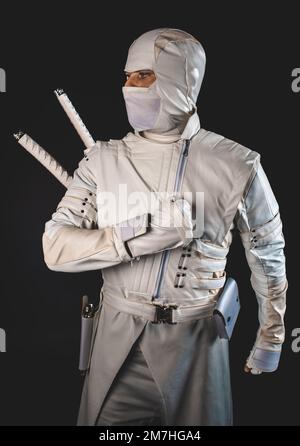 Ninja posa per una foto su uno sfondo nero, un ninja maschio in un kimono bianco. Foto Stock