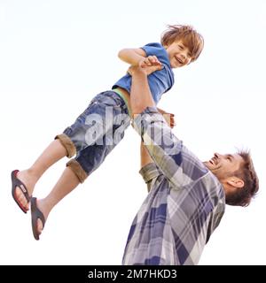 Quando cresco im andando essere forte come papà. un giovane padre che solleva il figlio in aria. Foto Stock