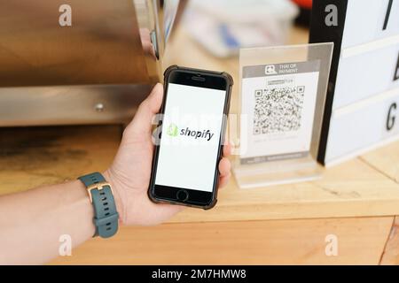 CHIANG mai, THAILANDIA - 15 ottobre 2022 : il maschio tiene iPhone 6s con l'applicazione Shopify sullo schermo in caffetteria. Shopify è un e-commercio Foto Stock