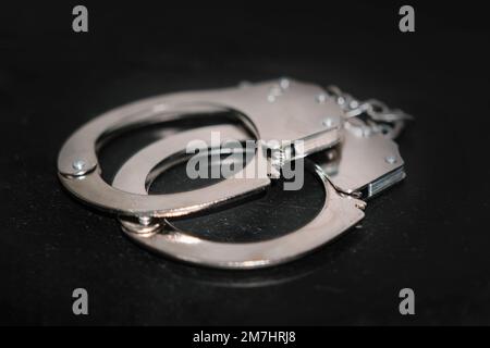 il concetto di arresto e criminalità. manette in metallo su sfondo nero da tavolo Foto Stock
