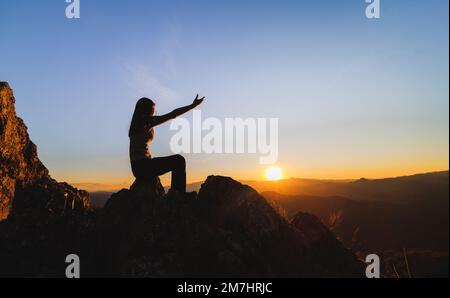 Silhouette della donna cristiana che prega a mano, spiritualità e religione, l'uomo che prega a dio. Concetto di Cristianesimo. Libertà e avventura di viaggio. Foto Stock