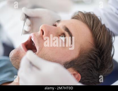 Attendere pazientemente per vedere se ha bisogno di qualche lavoro fatto. un giovane al dentista. Foto Stock