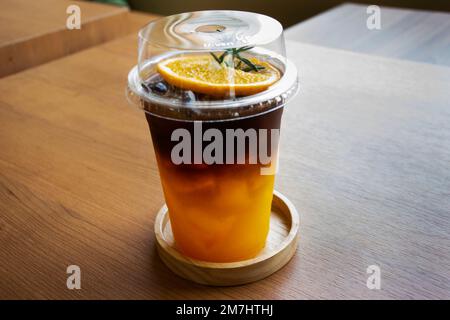 Caffè nero espresso servito con succo d'arancia e ghiaccio freddo in una tazza di vetro di plastica per i viaggiatori thailandesi mangiare e bevande nella caffetteria classica r Foto Stock