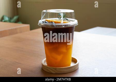 Caffè nero espresso servito con succo d'arancia e ghiaccio freddo in una tazza di vetro di plastica per i viaggiatori thailandesi mangiare e bevande nella caffetteria classica r Foto Stock