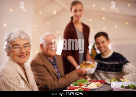 Ama servire la sua famiglia il giorno di Natale. Una giovane donna attraente che ospita il pranzo di famiglia il Natale. Foto Stock