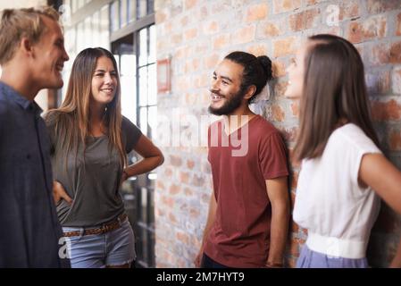 Allungare le gambe tra una lezione e l'altra. un gruppo diversificato di amici in piedi in un corridoio. Foto Stock