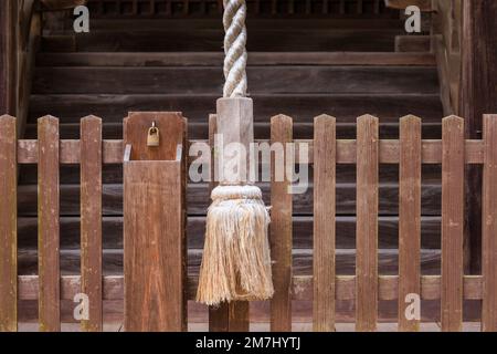 Grande corda per campanella ad anello al tempio giapponese e piccolo lucchetto su recinzione di legno Foto Stock
